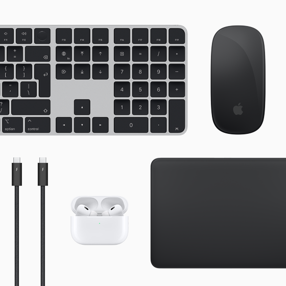 Pogled odozgo na dodatnu opremu za Mac: Magic Keyboard, Magic Mouse, Magic Trackpad, AirPods i Thunderbolt kablove